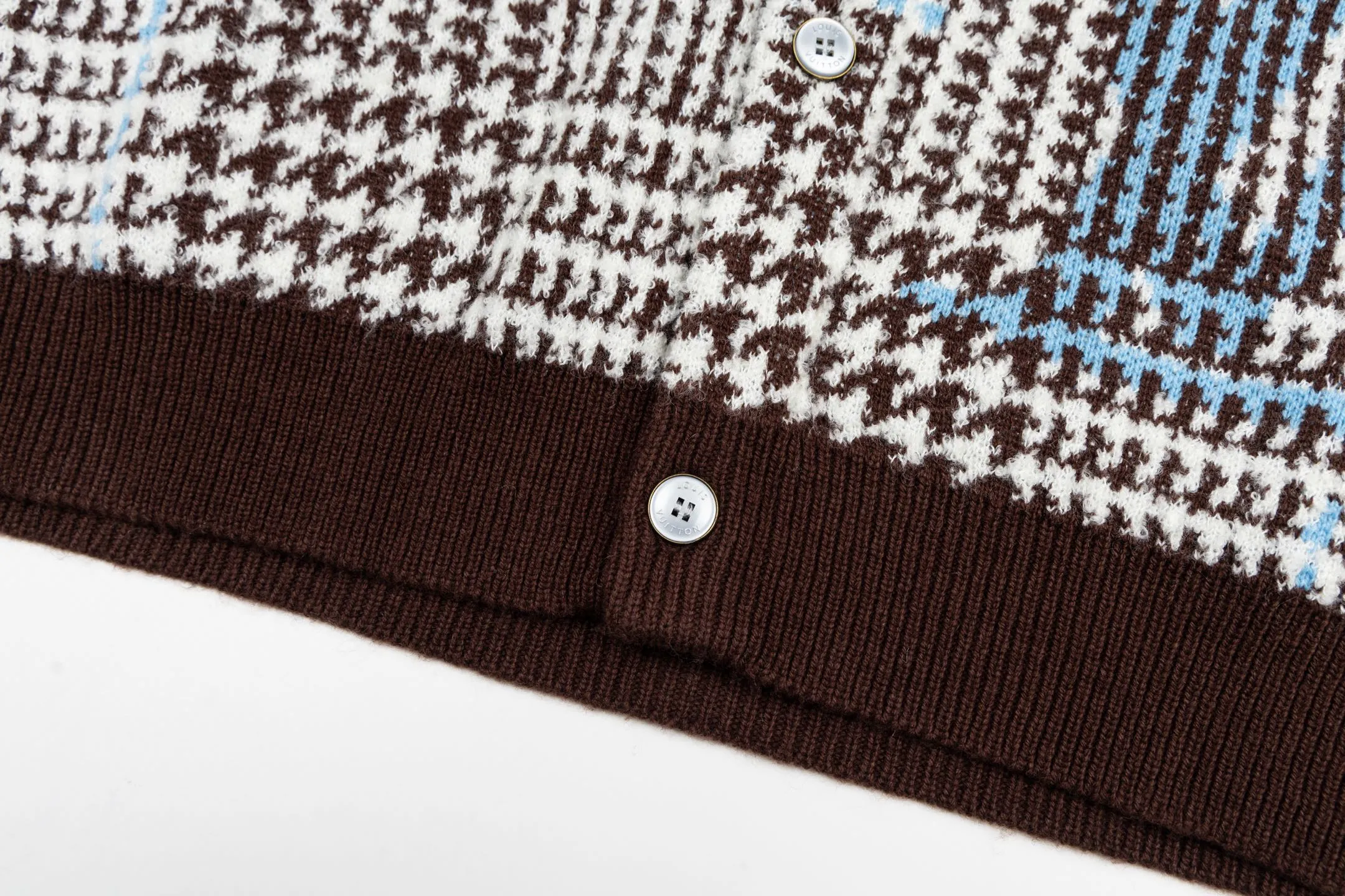 🅿️570 1v 26SS houndstooth letter intarsia V-neck knitted cardigan. The original version was purchased for 14,743 and developed. The fabric is made of yarn fabric made of 69% sheep wool blended with 31% nylon. The main pattern is woven with a full-width jacquard process, which interweaves the houndstooth pattern with light blue line texture. At the same time, the brand logo elements are integrated into the body through the intarsia process, and the edges of the pattern are connected delicately and seamlessly. The collar, cuffs and hem are made of 100% sheep wool ribbed fabric, and are edged with double-needle seaming technology, which has both elasticity and shaping effect. The front placket is equipped with natural-textured buttons, and the side seam pockets use invisible stitching technology to blend naturally with the jacquard texture of the body. The overall shape is shaped through three-dimensional tailoring, and the shoulders are stitched with seamless stitching to ensure fit and comfort. The entire piece is finished with handcrafted details in an Italian workshop, showing the craftsmanship precision of high-quality knitted items. The overall wiring is straight and delicate, the fabric is comfortable and soft, and the color is consistent without color difference. It can be matched with the same style to create a fashionable look and control various occasions. Customized accessories, complete with three standards, the same style for men and women. Size:S-M-L-XL